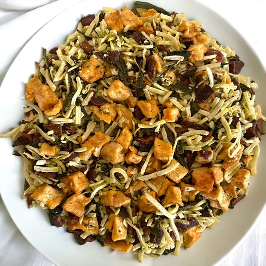 The image is showing dried apples mixed with herbs and toasted coconut on white plate.