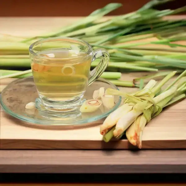A warm cup of Jaroma Lemongrass and Ginger Tea served on a glass saucer, surrounded by fresh lemongrass stalks and slices, evoking a soothing, aromatic atmosphere perfect for relaxation. The rich green hue of the tea contrasts with the vibrant yellow-green lemongrass, adding a natural touch to the scene.