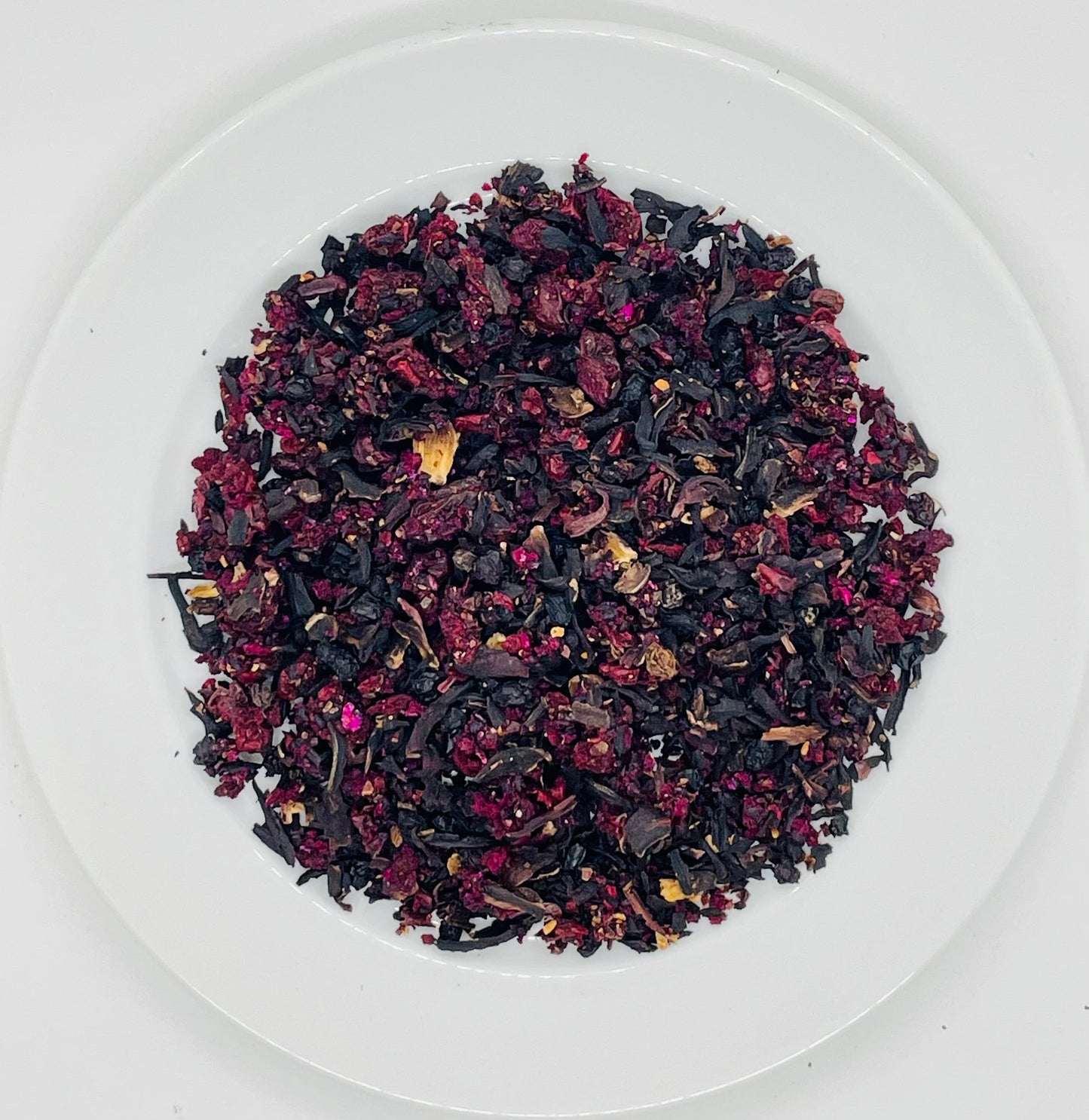 Image of a Black Cherry Berry tea blend on a ceramic plate with colourful dry fruit and berries
