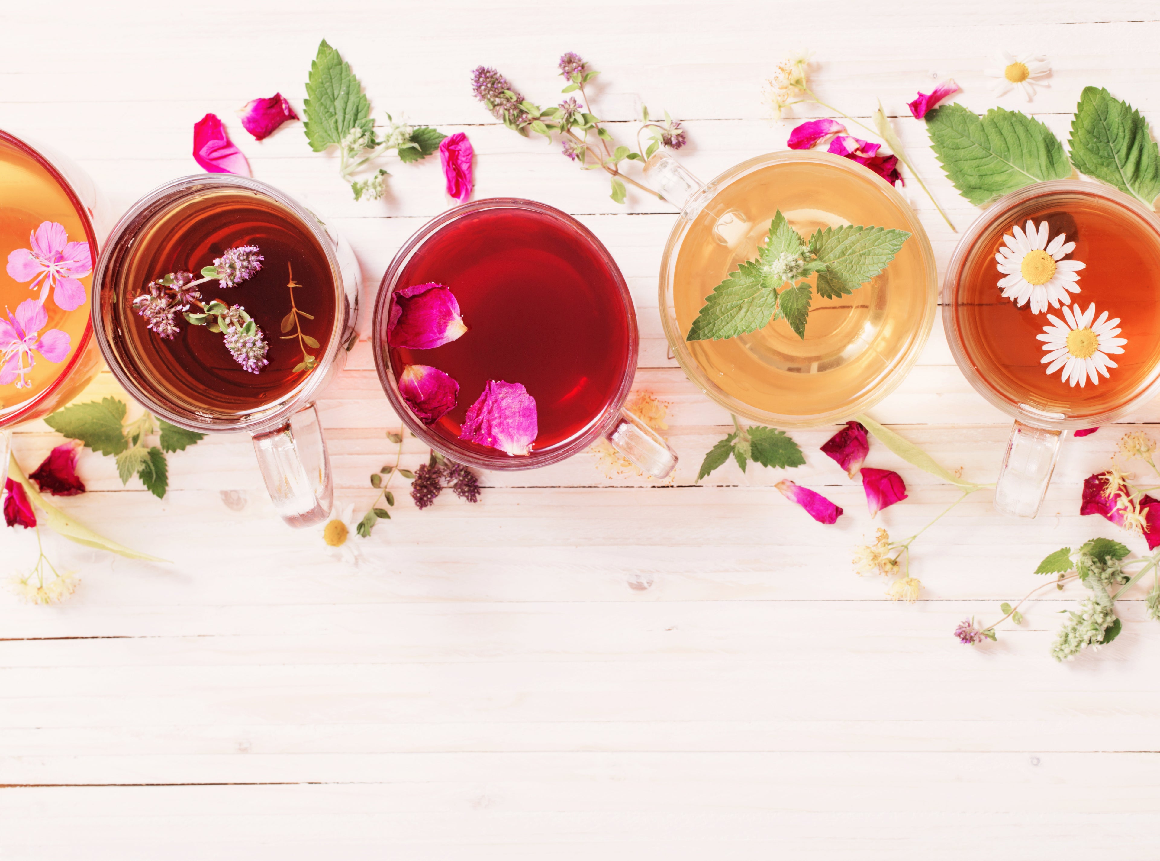 Image of a variety of freshly brewed teas in clear glass cups so you can see the vibrant colours of the tea and almost smell it through the screen.