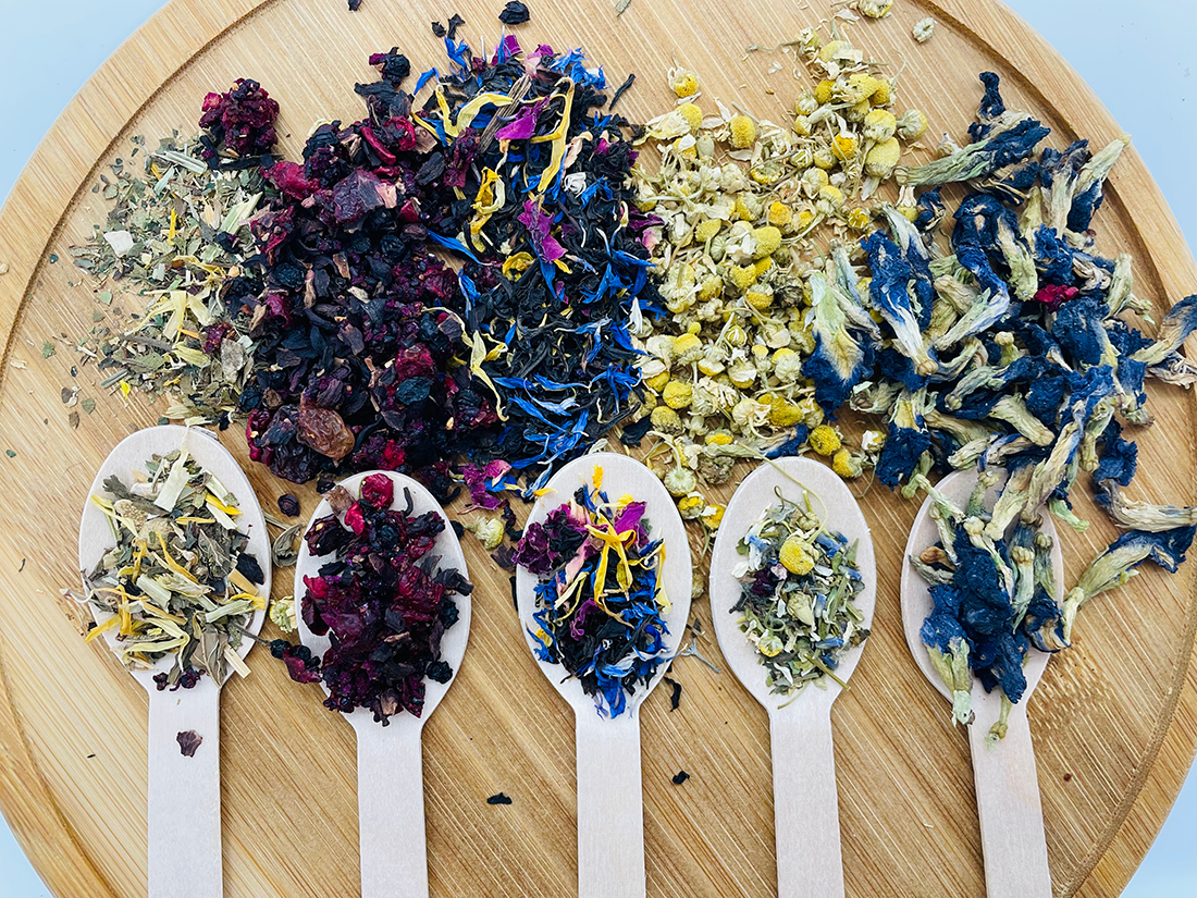 A picture of fruit and herbal Jaroma tea blends in their vibrant colours displayed on the wooden spoons